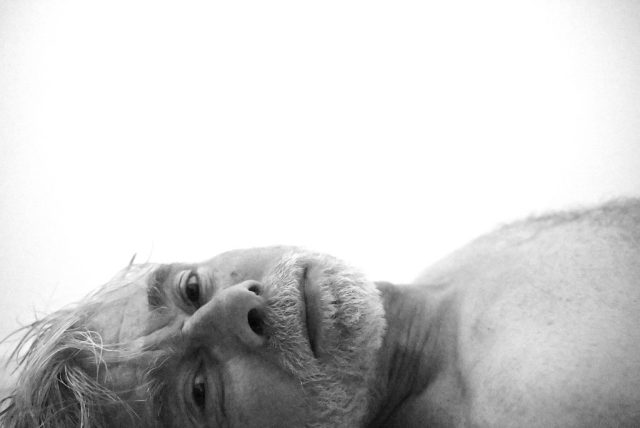 "Black-and-white photograph capturing a tender and vulnerable moment, focusing on the raw emotion and texture of skin and facial hair. The image conveys a sense of intimacy and authenticity, emphasizing the unfiltered expression of identity and connection.